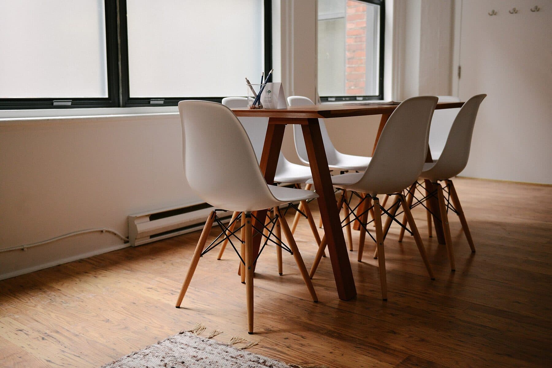 A meeting room with six chairs set around a wooden table by a window.
